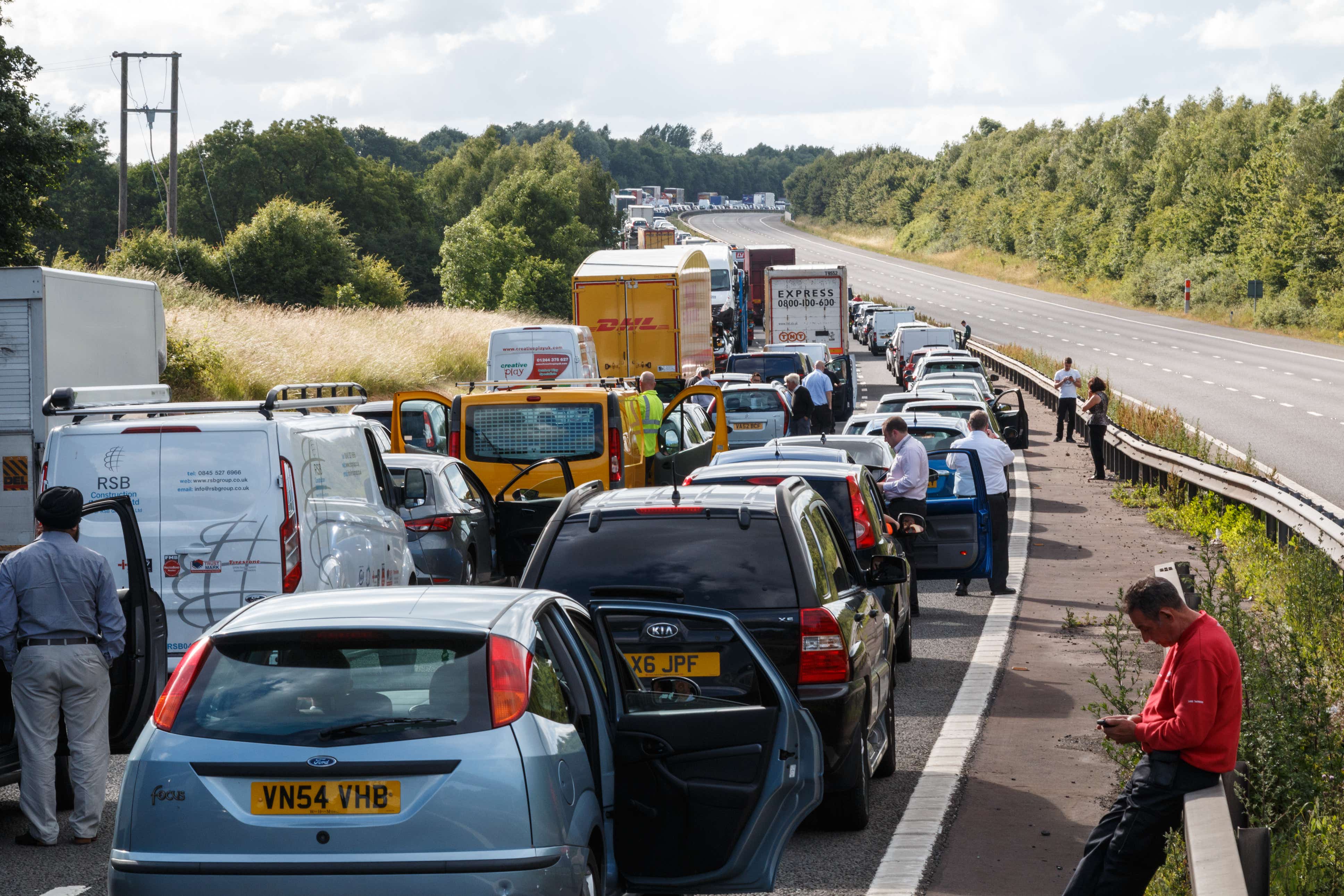Warwickshire,UK - June 28th 2015:Drivers standing next to lines of queing traffic in a motorway traffic jam after an accident. This happened on the M40 in England.