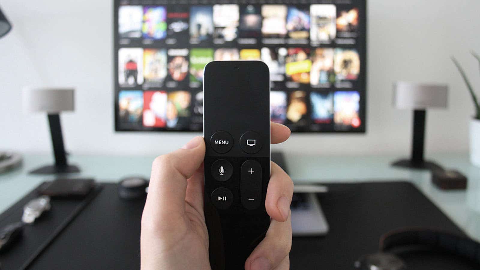 someone holding a streaming stick remote in front of their TV