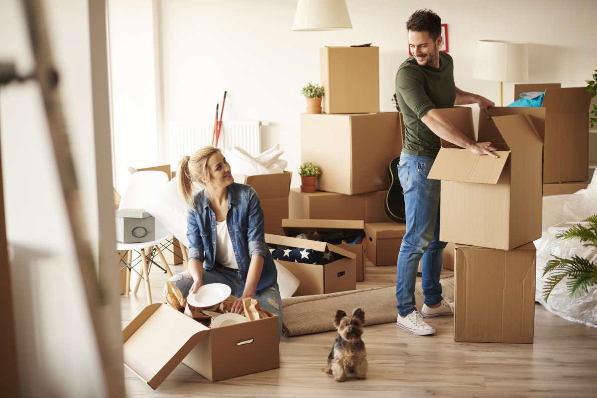 Couple with packaging boxes moving home + dog