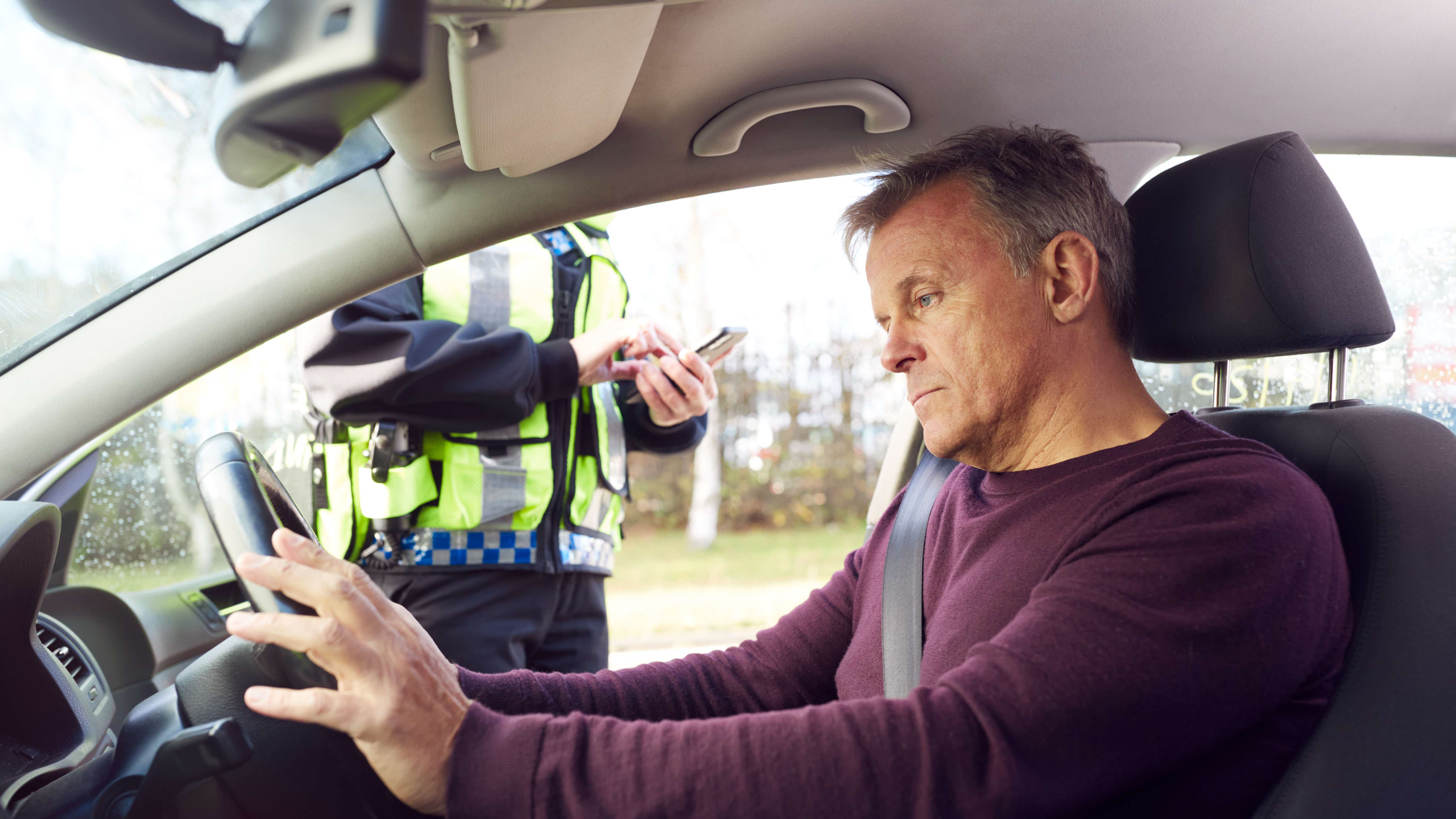 Agente di polizia che scrive un biglietto o emette una multa a un autista di auto maschile
