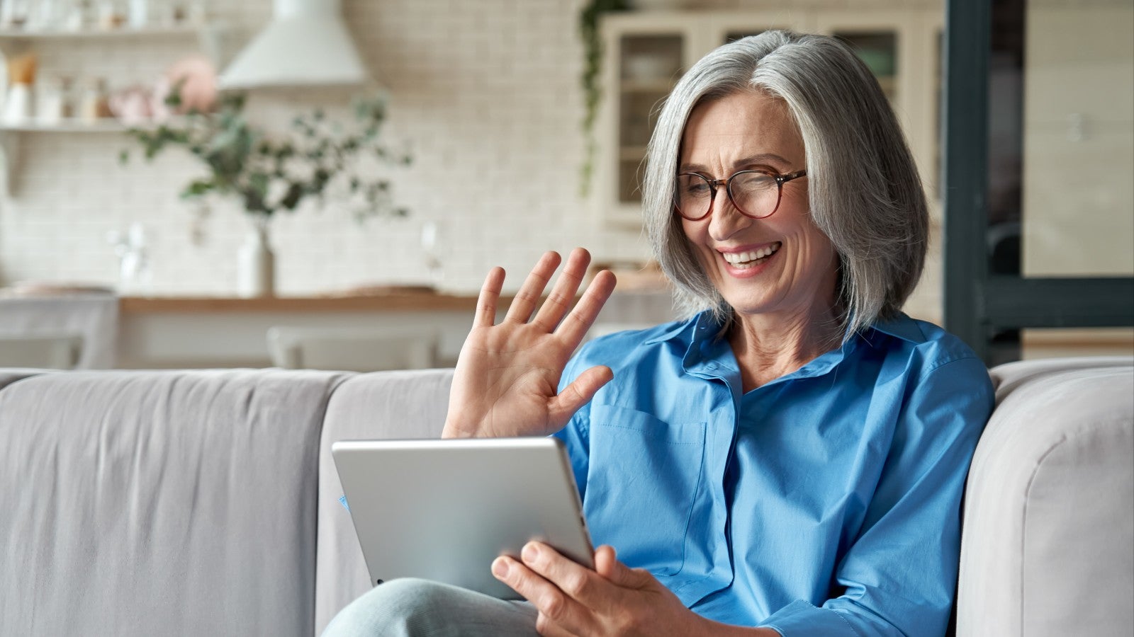 Happy 60s older mature middle aged adult woman using digital tablet on Wi-Fi