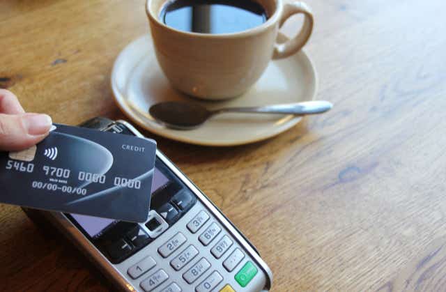 Contactless payment card, with hand holding credit card ready to pay at cafe coffee shop 