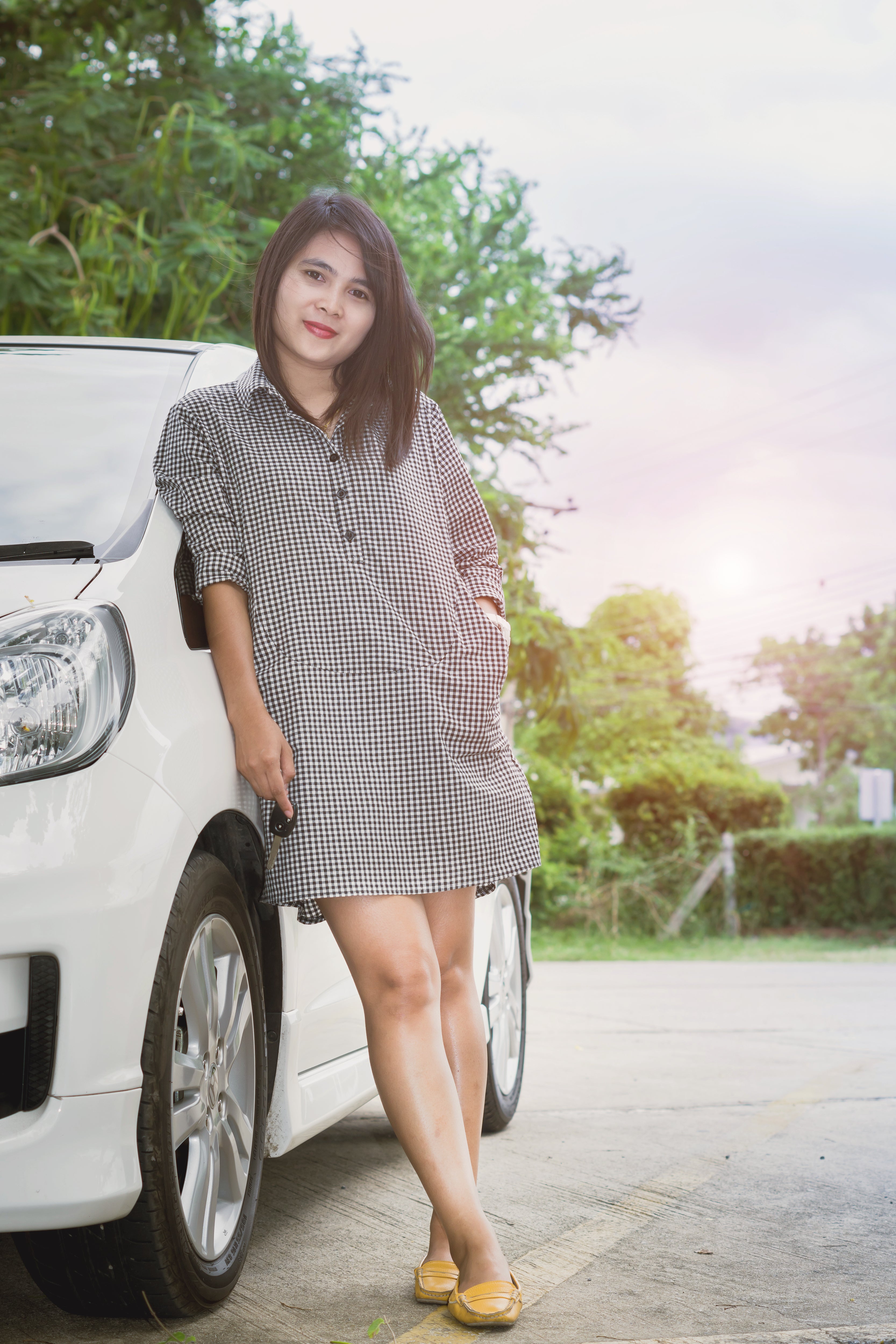 Retrato feliz sonriente joven atractiva mujer sosteniendo las llaves del coche y de pie cerca de nuevo coche blanco