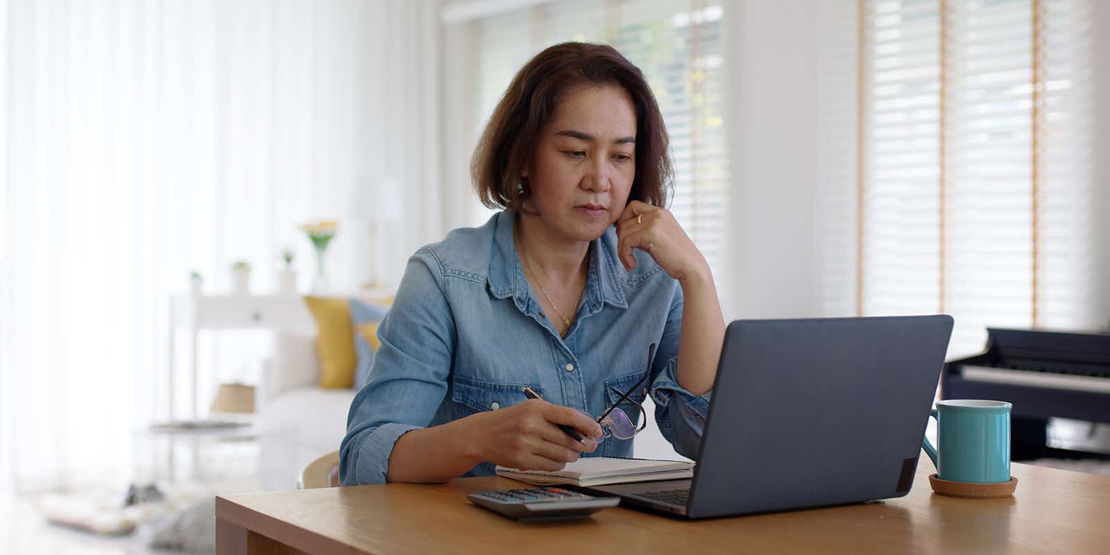 woman at home paying her bills looking concerned at her laptop