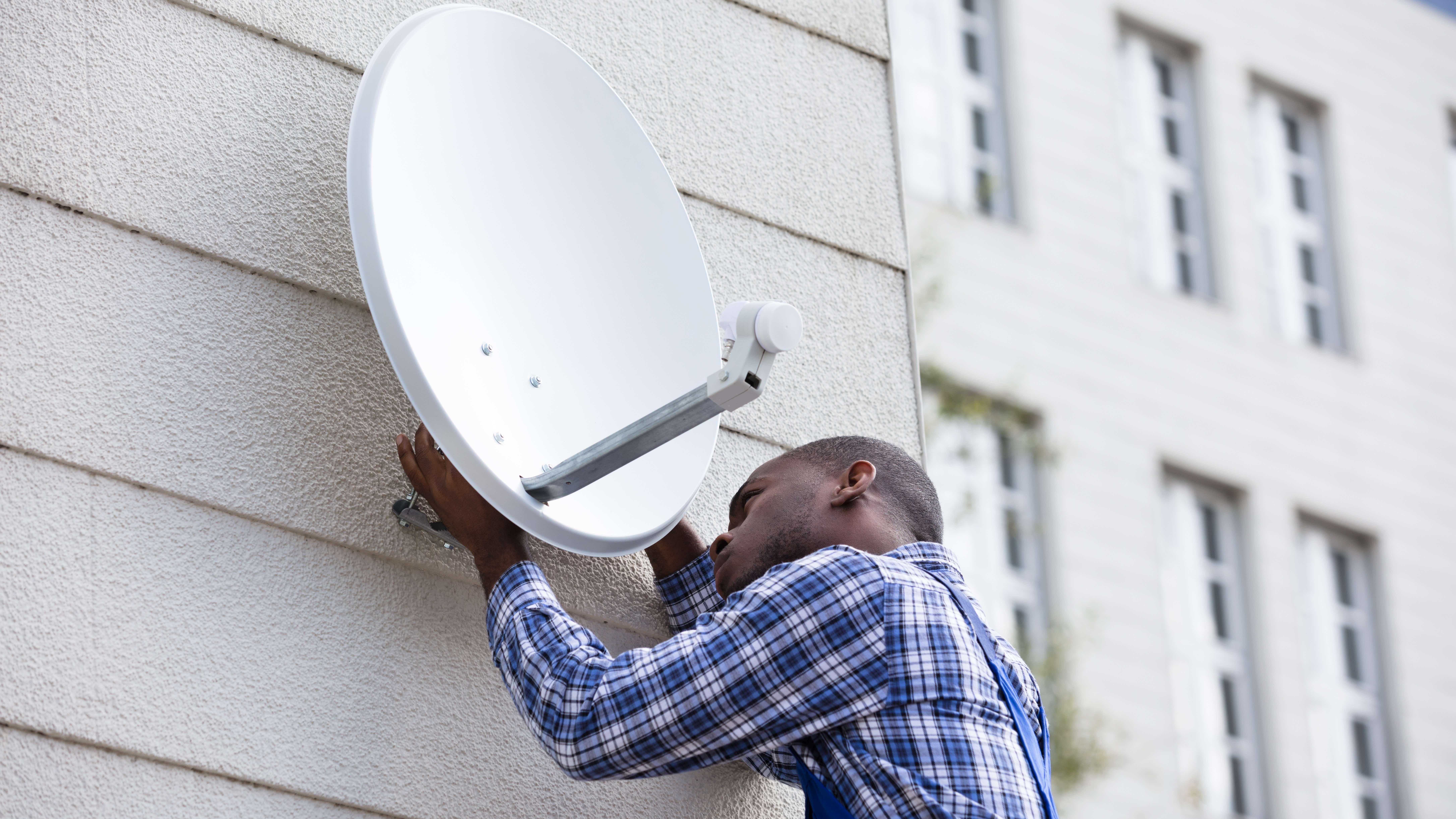 Young man installing a satellite dish in a block of flats