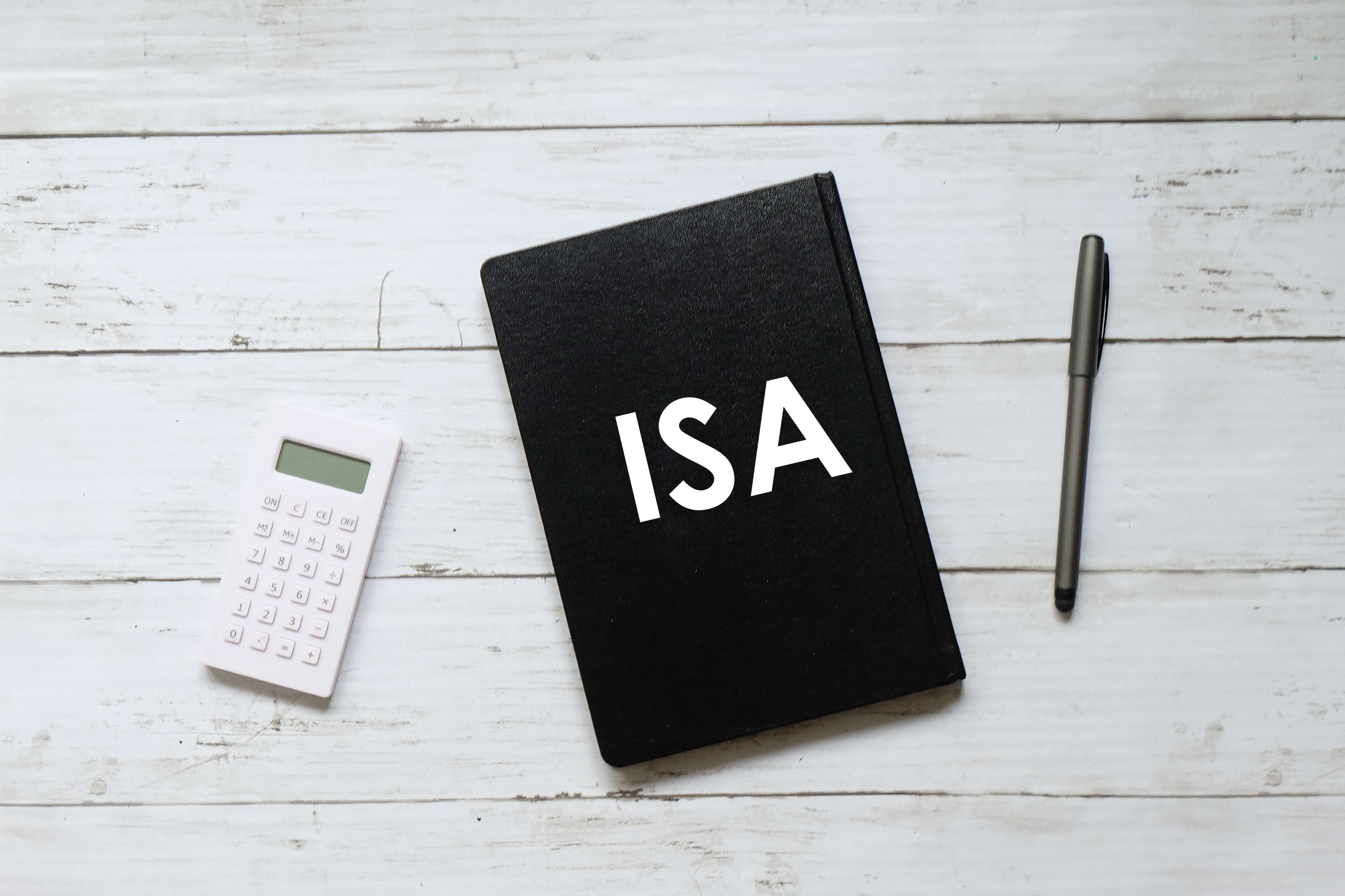Pen and notebook written with ISA (individual saving account) on white wooden background.