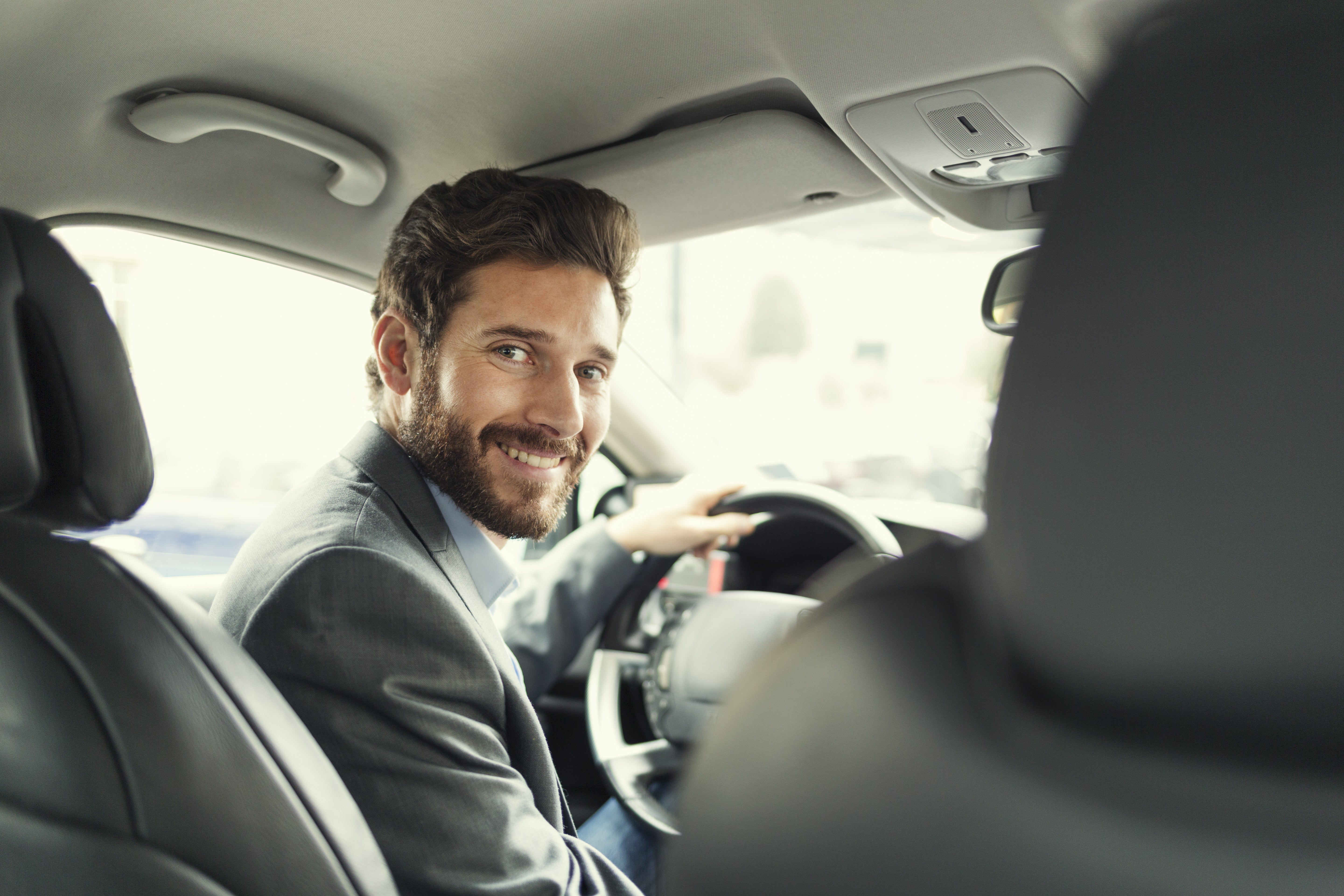 Un hombre de negocios con traje conduciendo un auto.