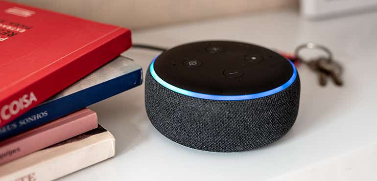 an amazon echo dot sitting on a desk with some books