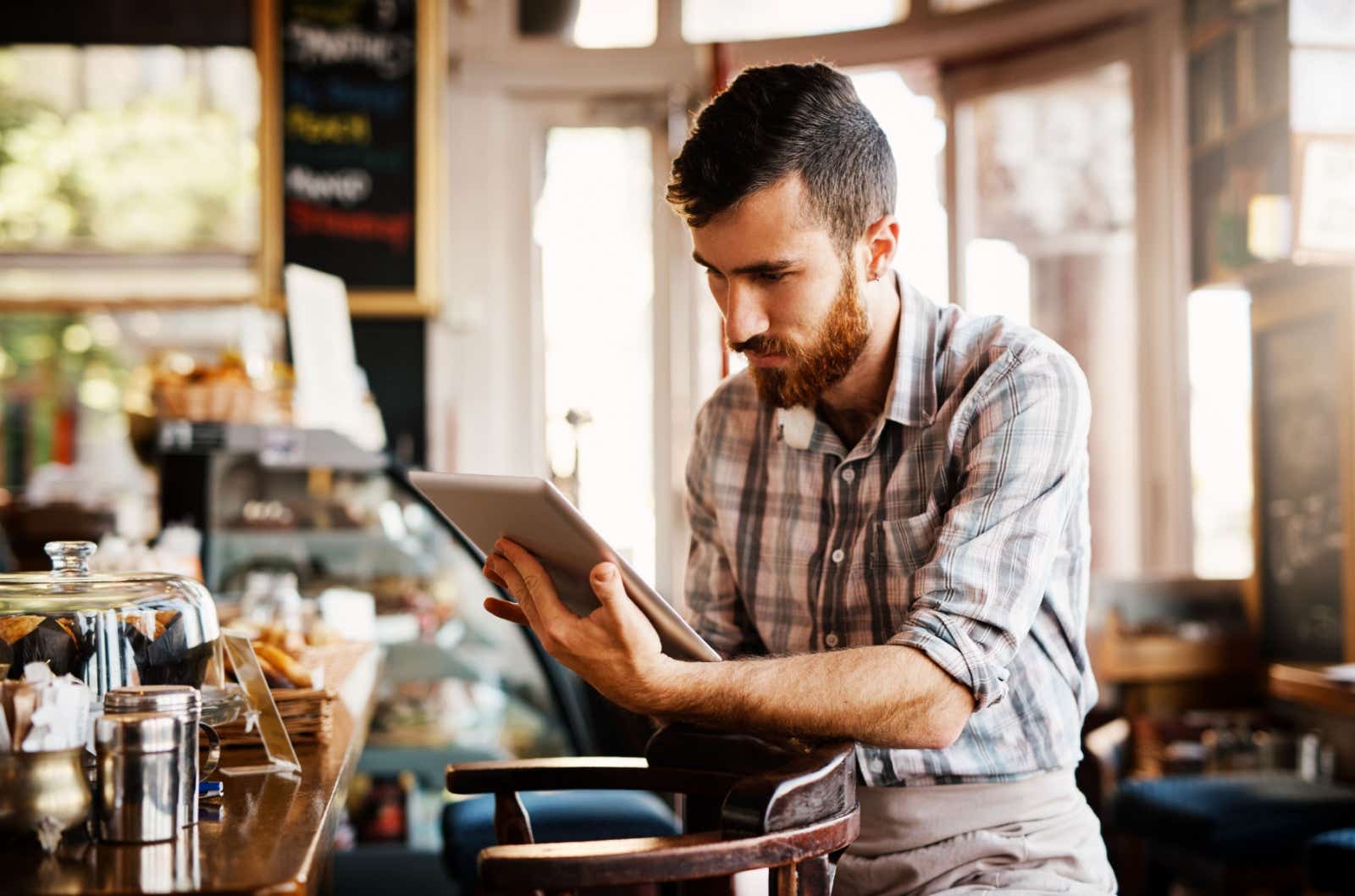 Coffee shop owners looking at his tablet screen
