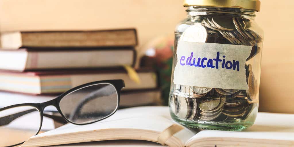 glasses on top of book next to jar with coins in stating education