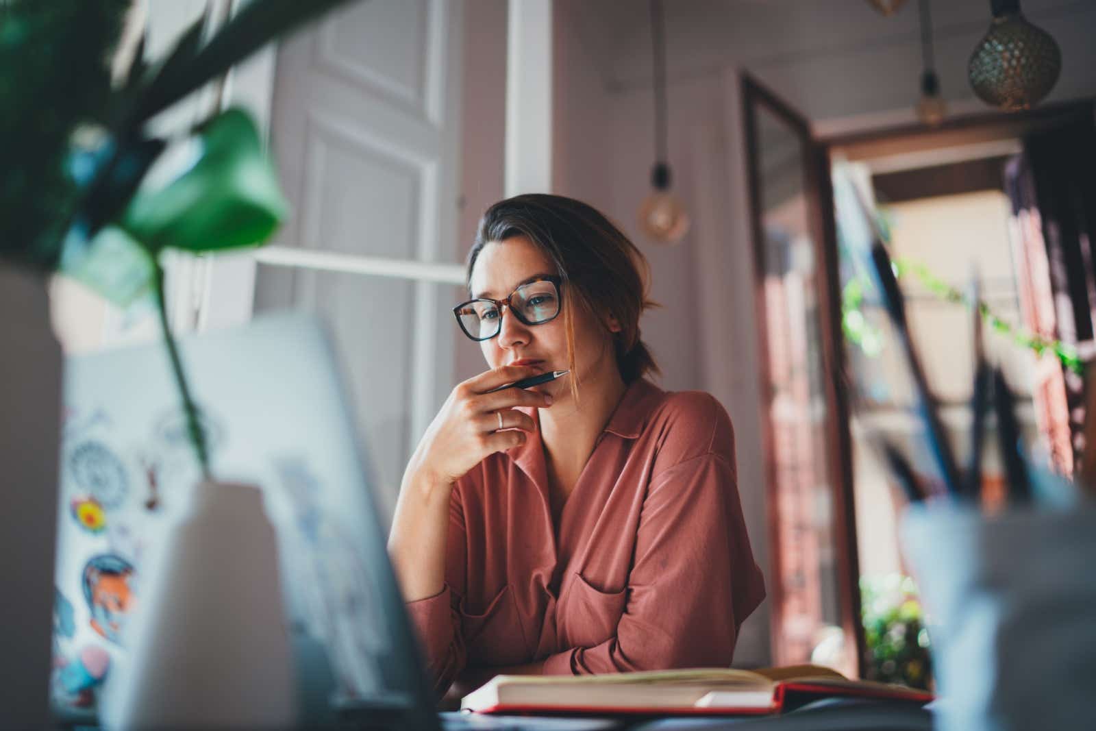 Pensive businesswoman working at a desk on a laptop at home