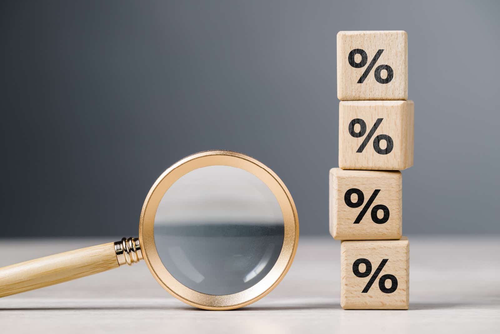 Magnifying glass next to a tower of wooden blocks with percentage signs marked on them