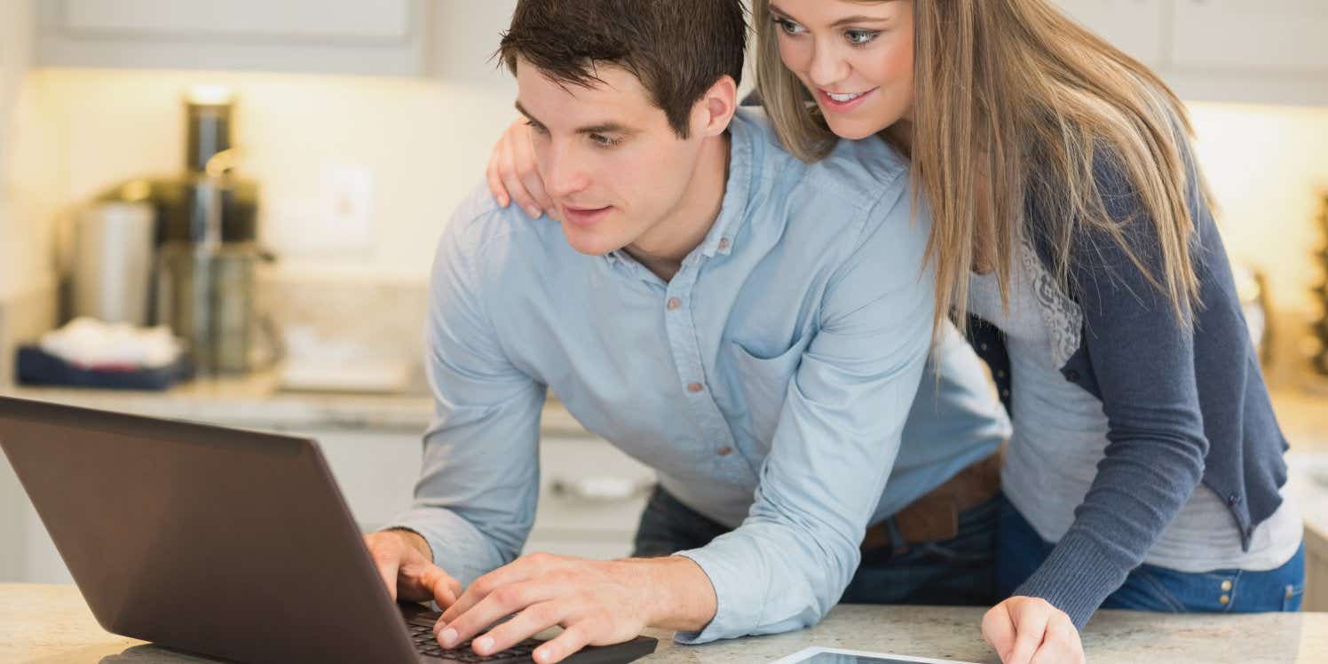 young-couple-using-laptop-in-kitchen