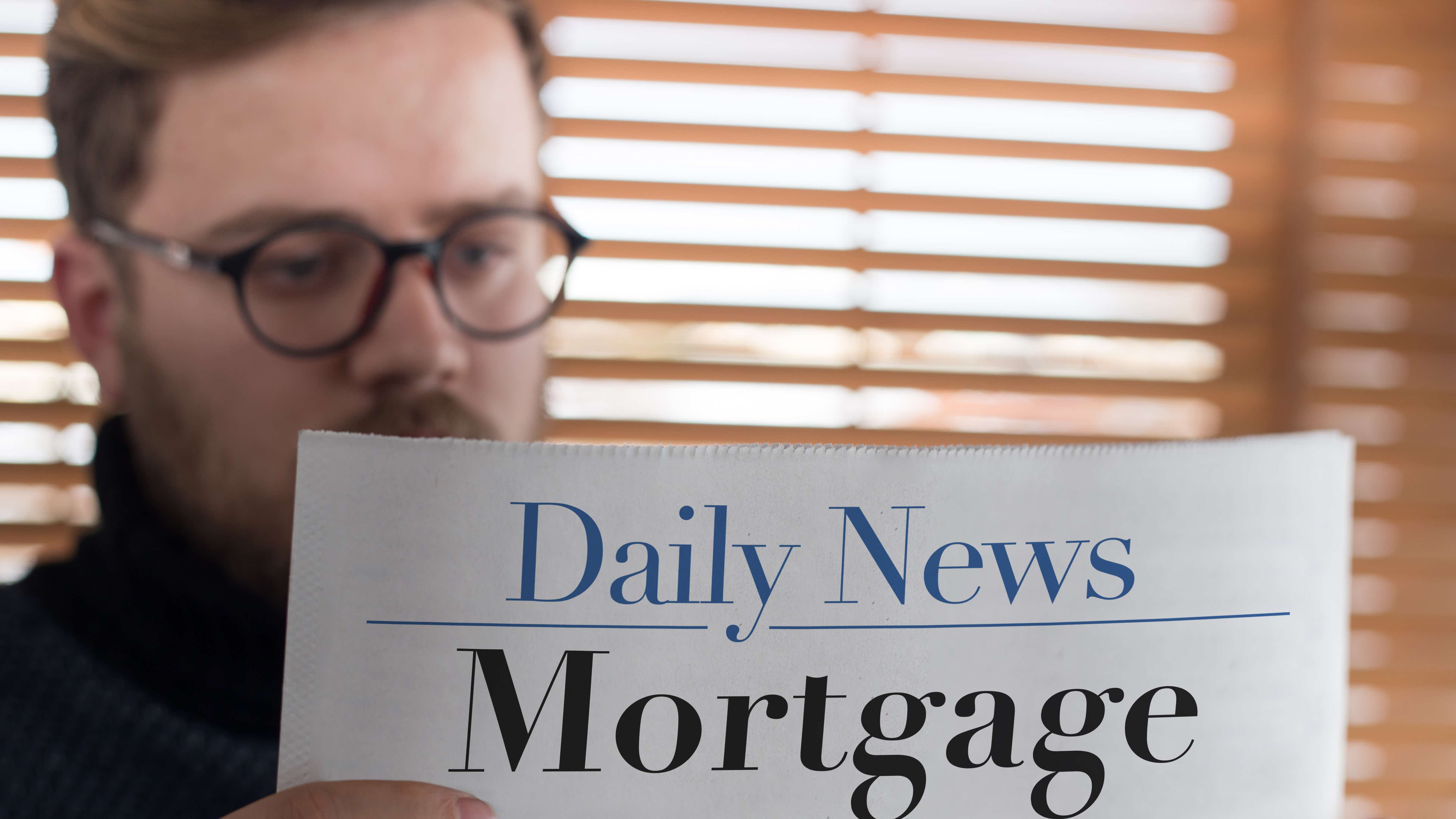 A close up of someone reading a newspaper titled 'daily news - mortgages'