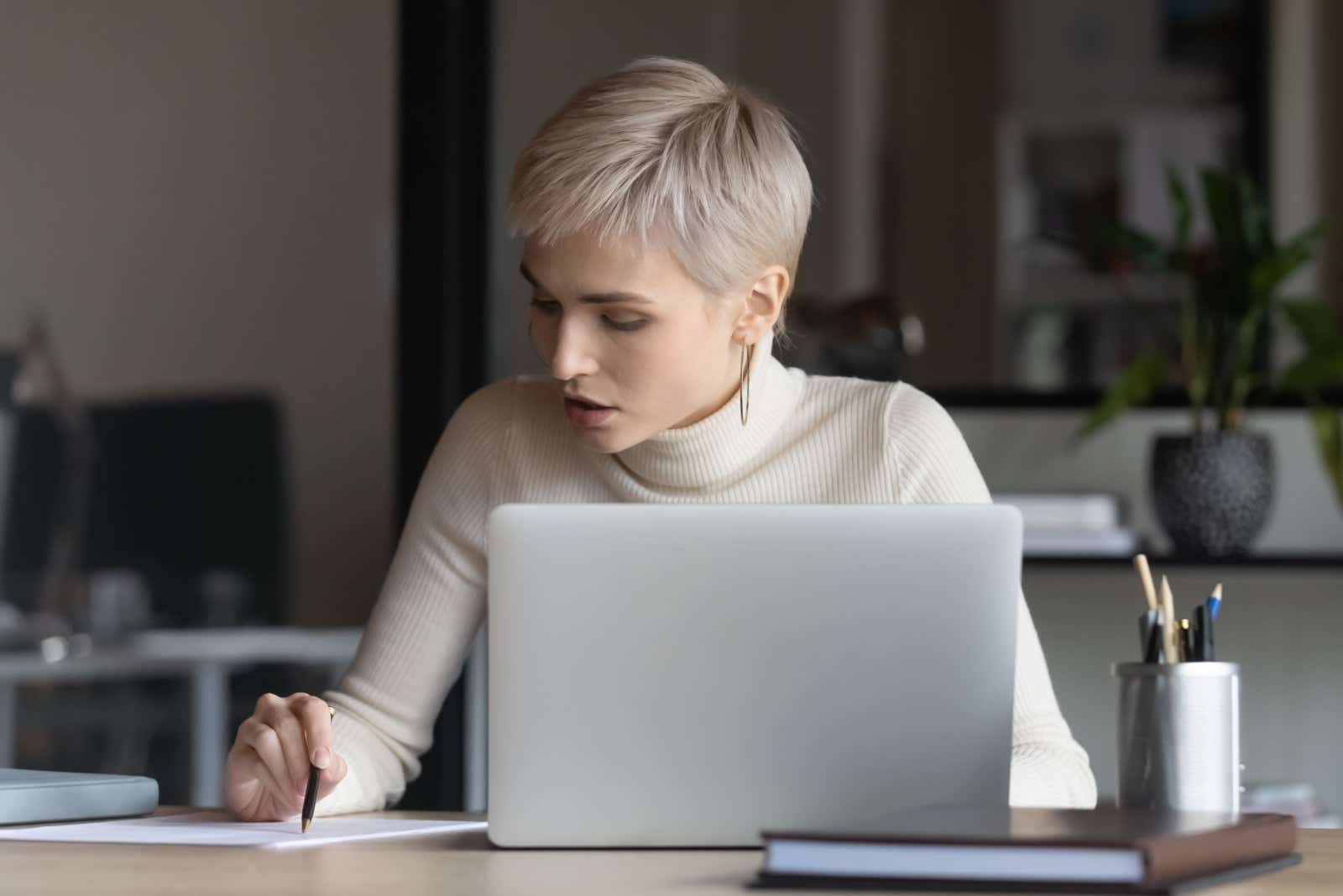 Woman looking at paperwork while working on her laptop