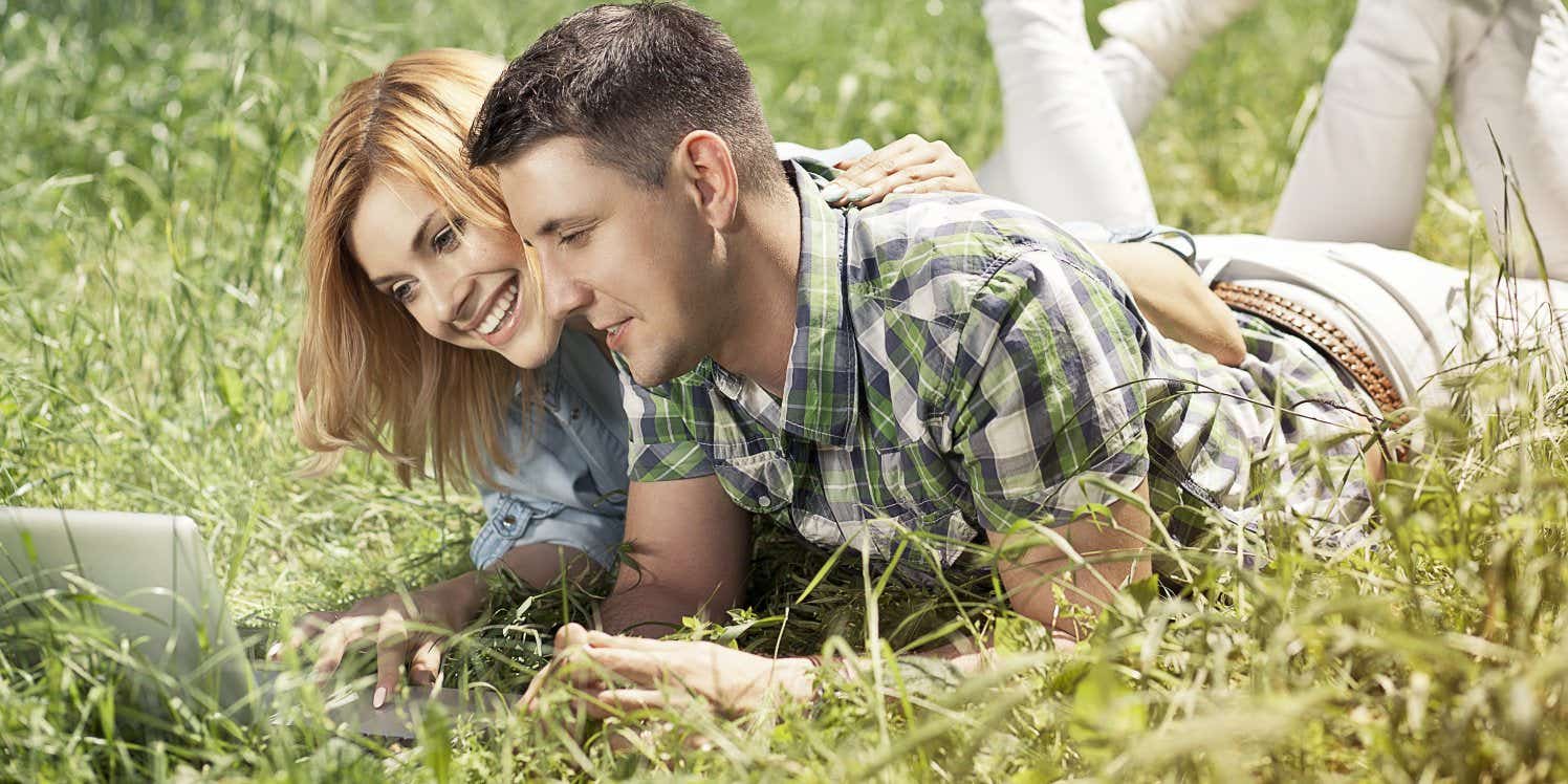 Young couple outside in garden using laptop