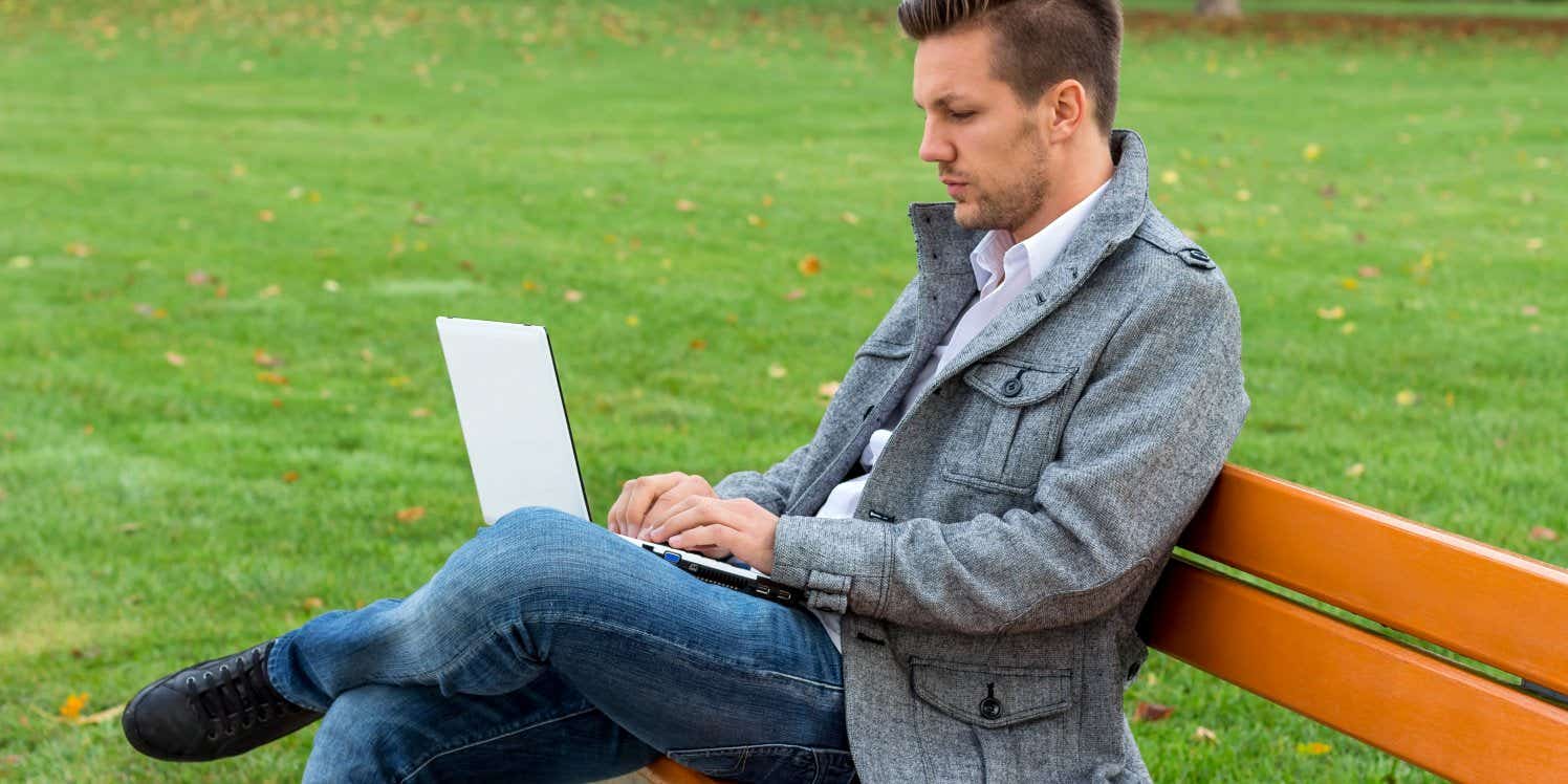 Man on park bench using laptop