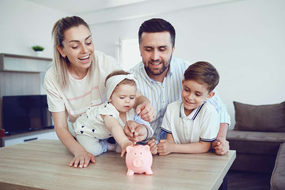 Family of four putting money into piggy bank