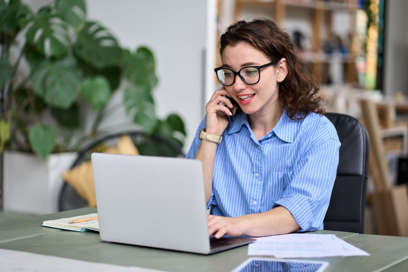 Young businesswoman talking on the phone while on her laptop