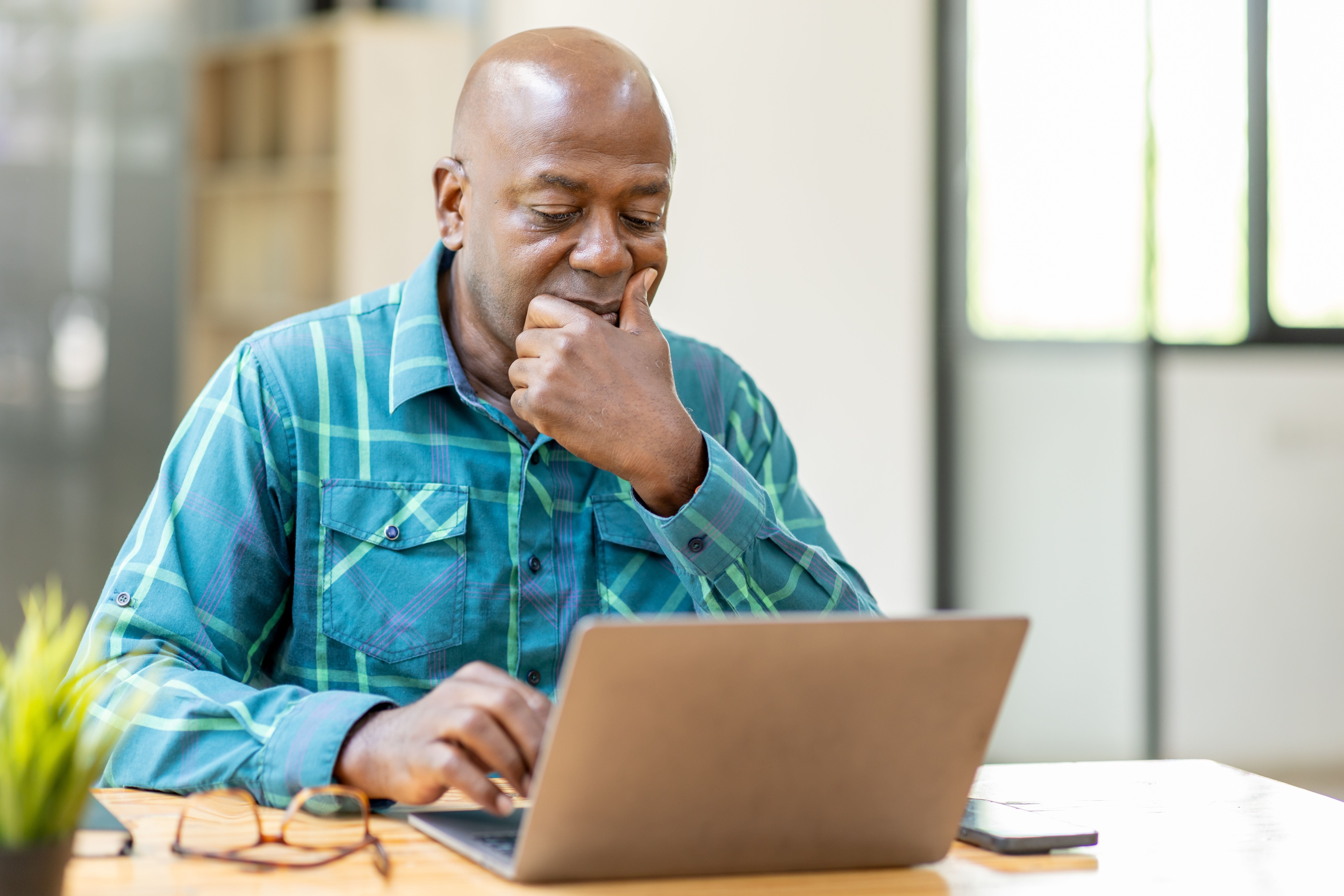 Pensive older businessman looking at his laptop screen