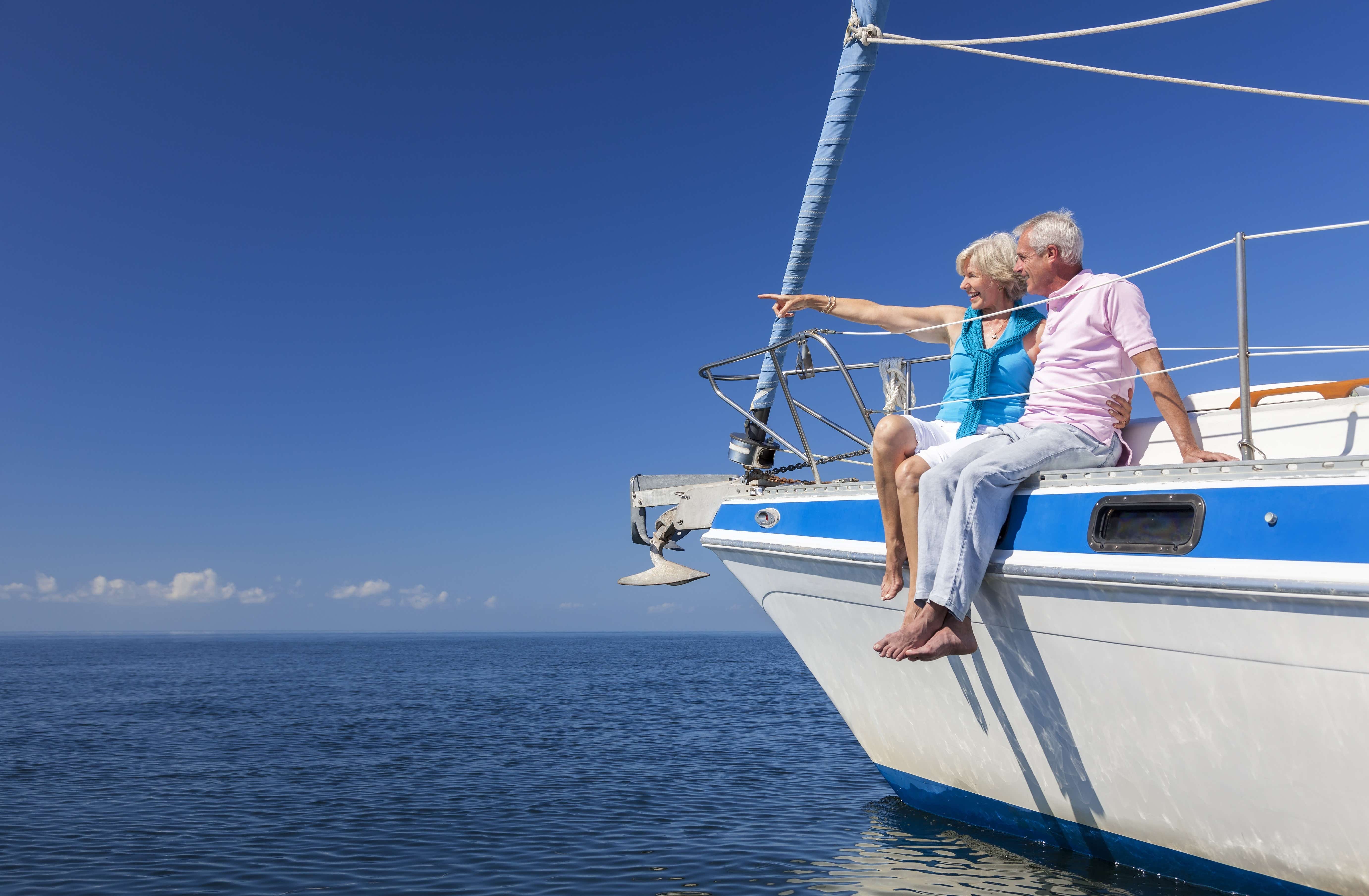 A happy couple sit on a yacht under clear blue skies