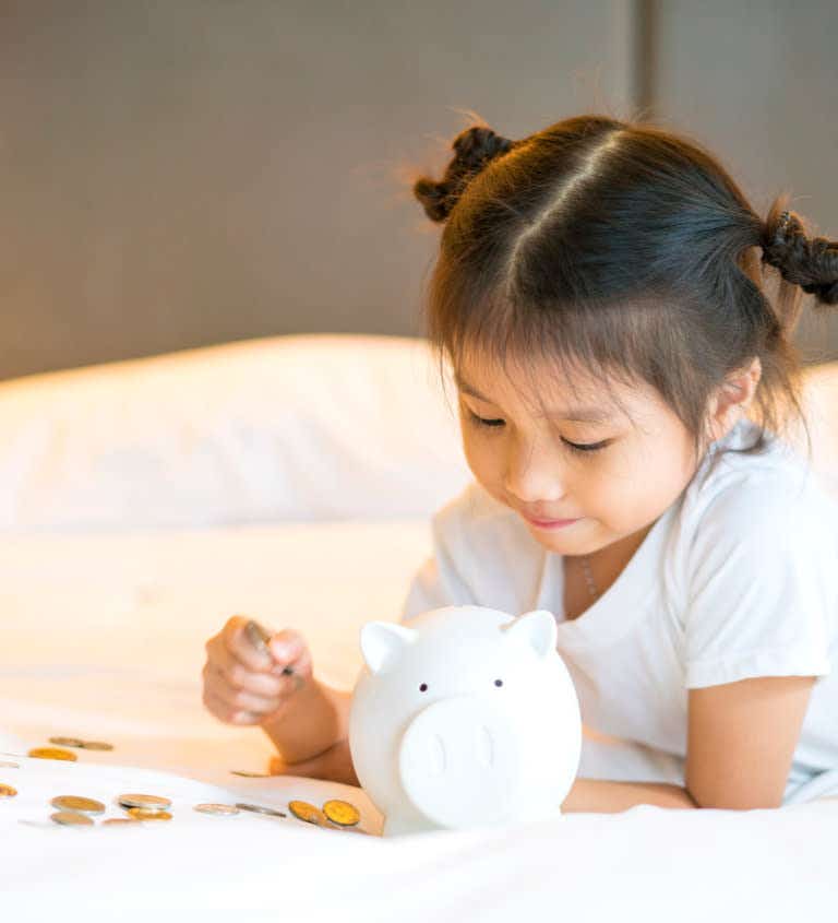 Young girl counting money for piggy bank