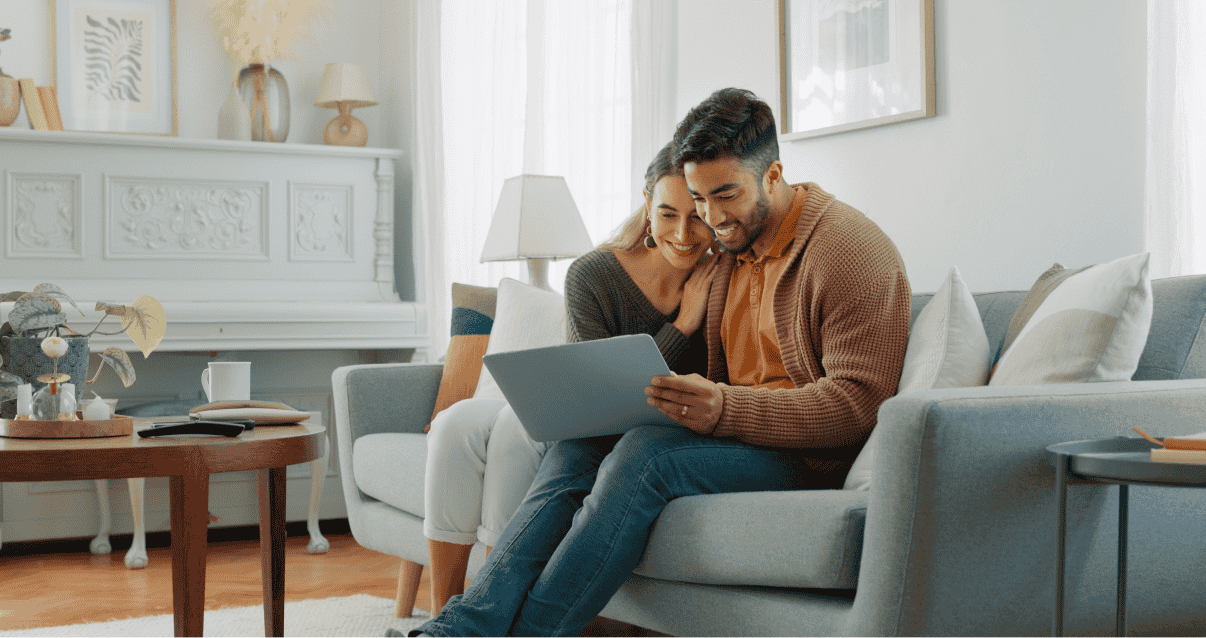 Couple sitting on a sofa looking at a laptop