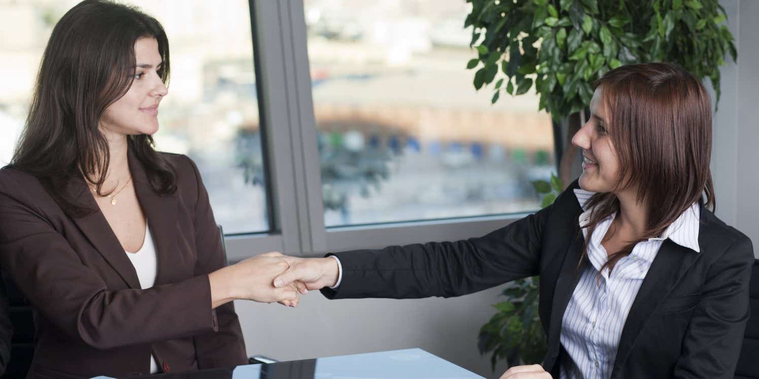 businesswomen-at-desk-handshake-office