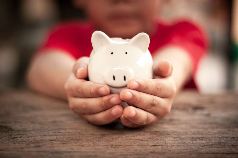 A child is holding a piggy bank