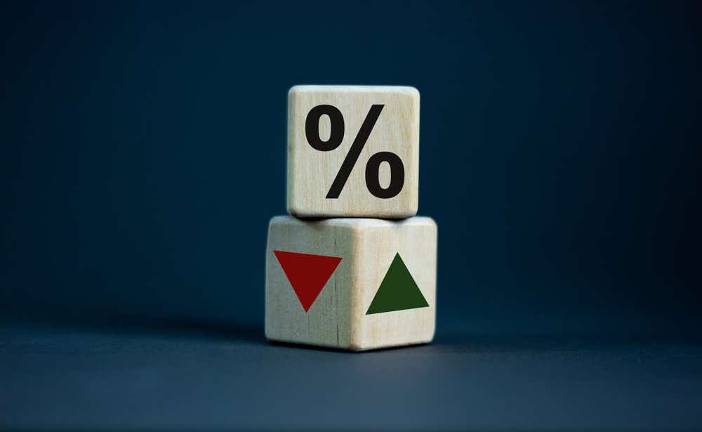 Two wooden blocks one with the percentage symbol and the other with a red arrow going down and a green arrow pointing up. 
