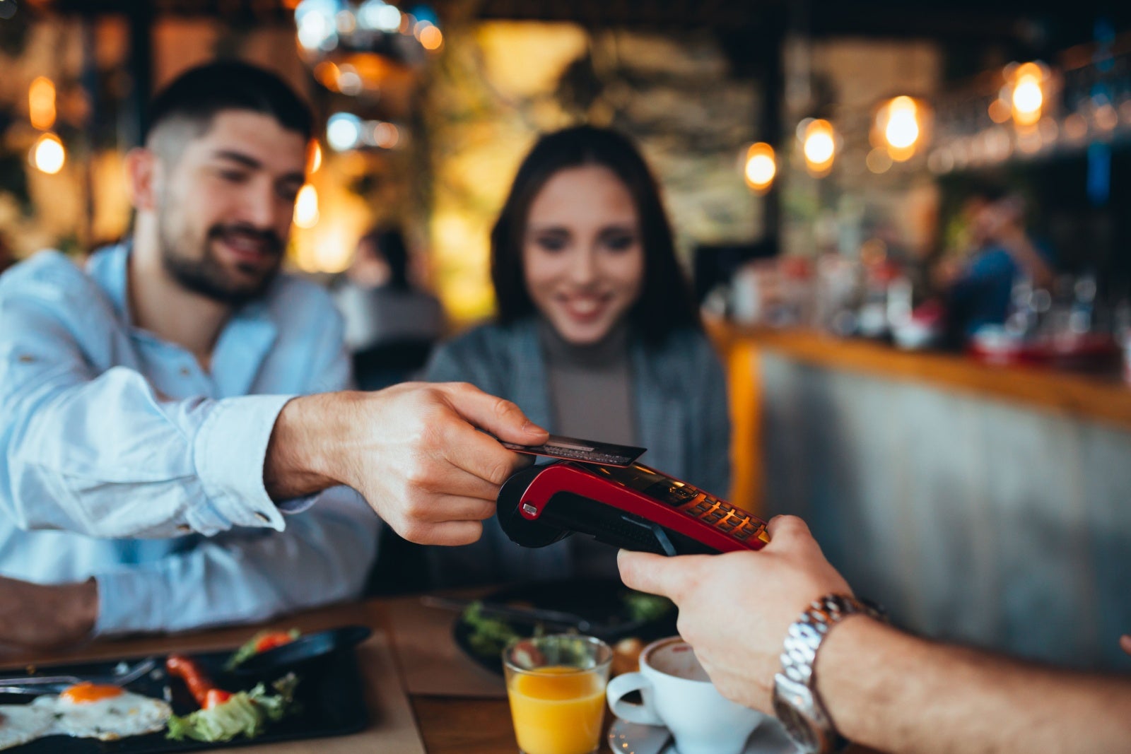Couple paying for a meal in a restaurant with a card. 