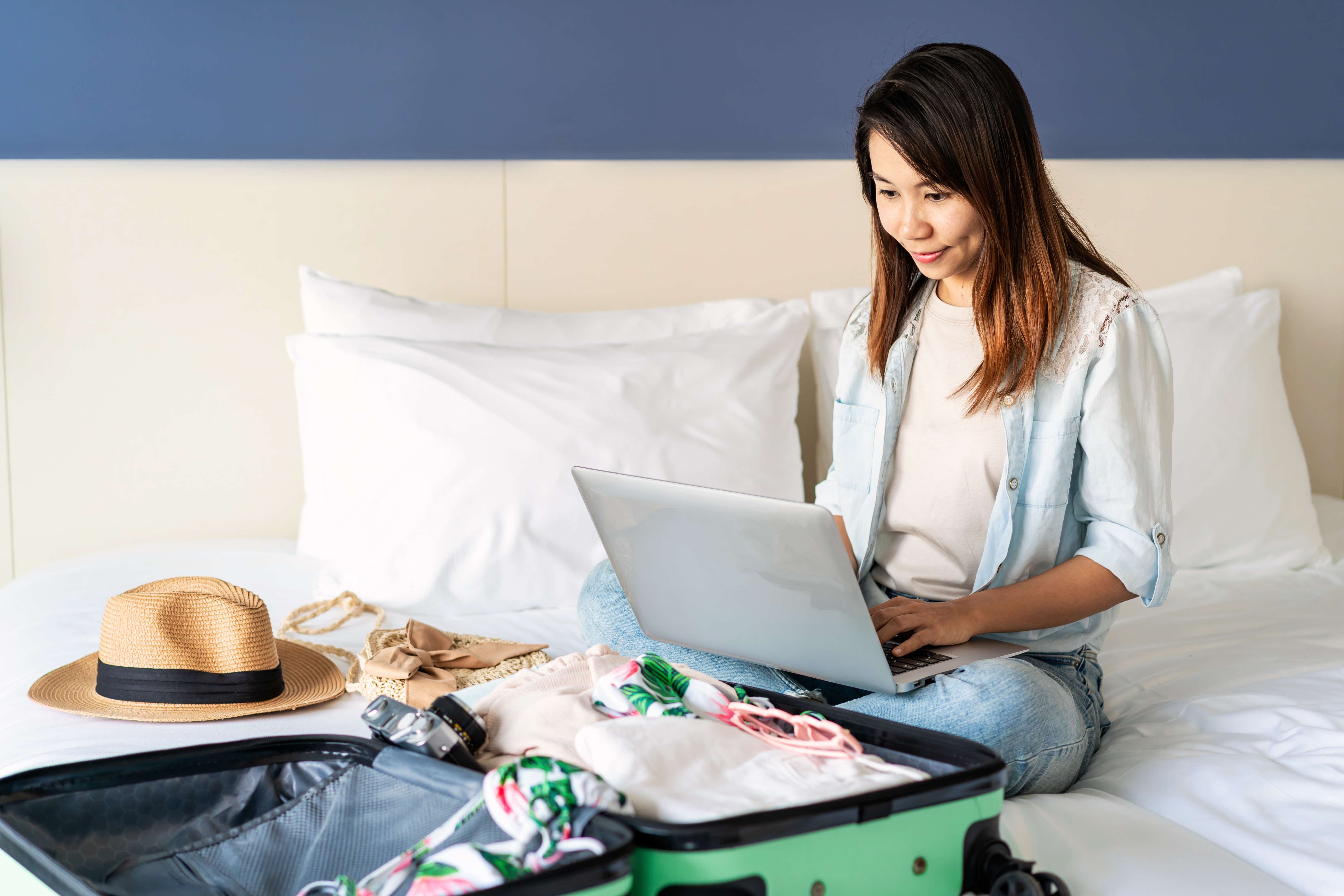 Young woman planning summer holiday trip and searching information or booking hotel on laptop.