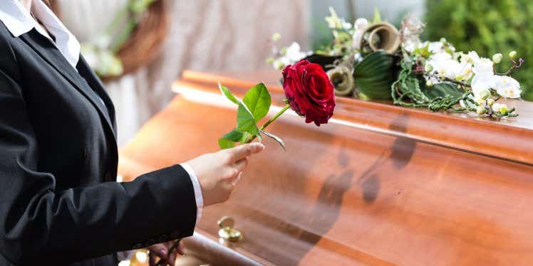 mourner-with-flower-stood-by-coffin