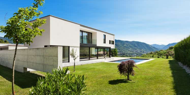 Modern villa with a garden and a pool in sunny weather.