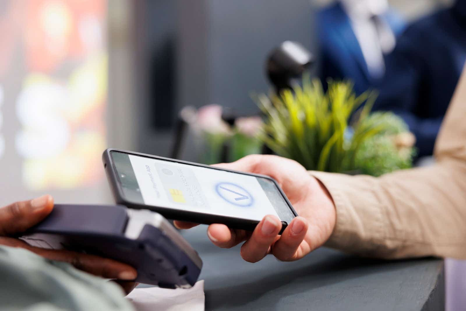 Person paying via a mobile card terminal with their smartphone.