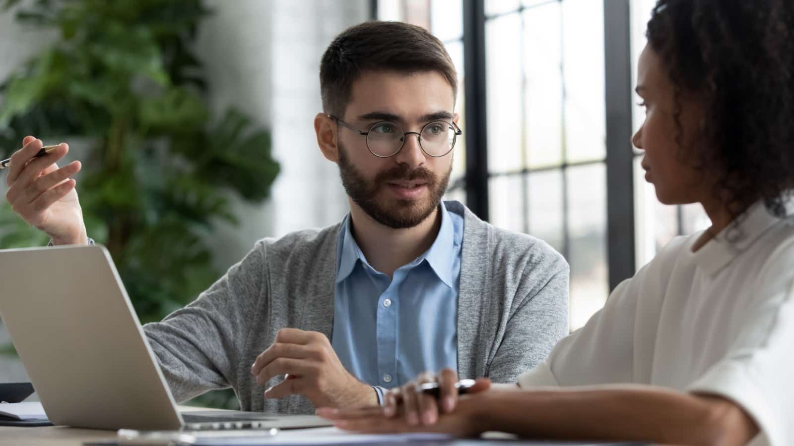 Man and woman in a meeting looking at a laptop. 