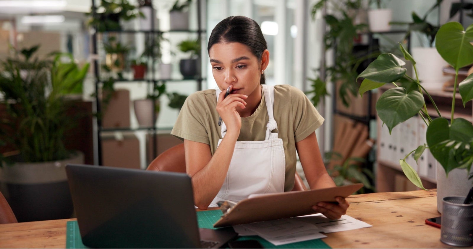 A florist in her shop ponders something on her laptop screen. 