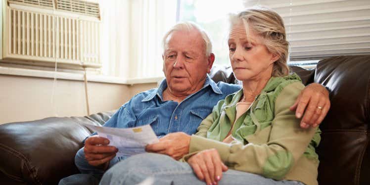 older-couple-looking-at-bills-on-sofa