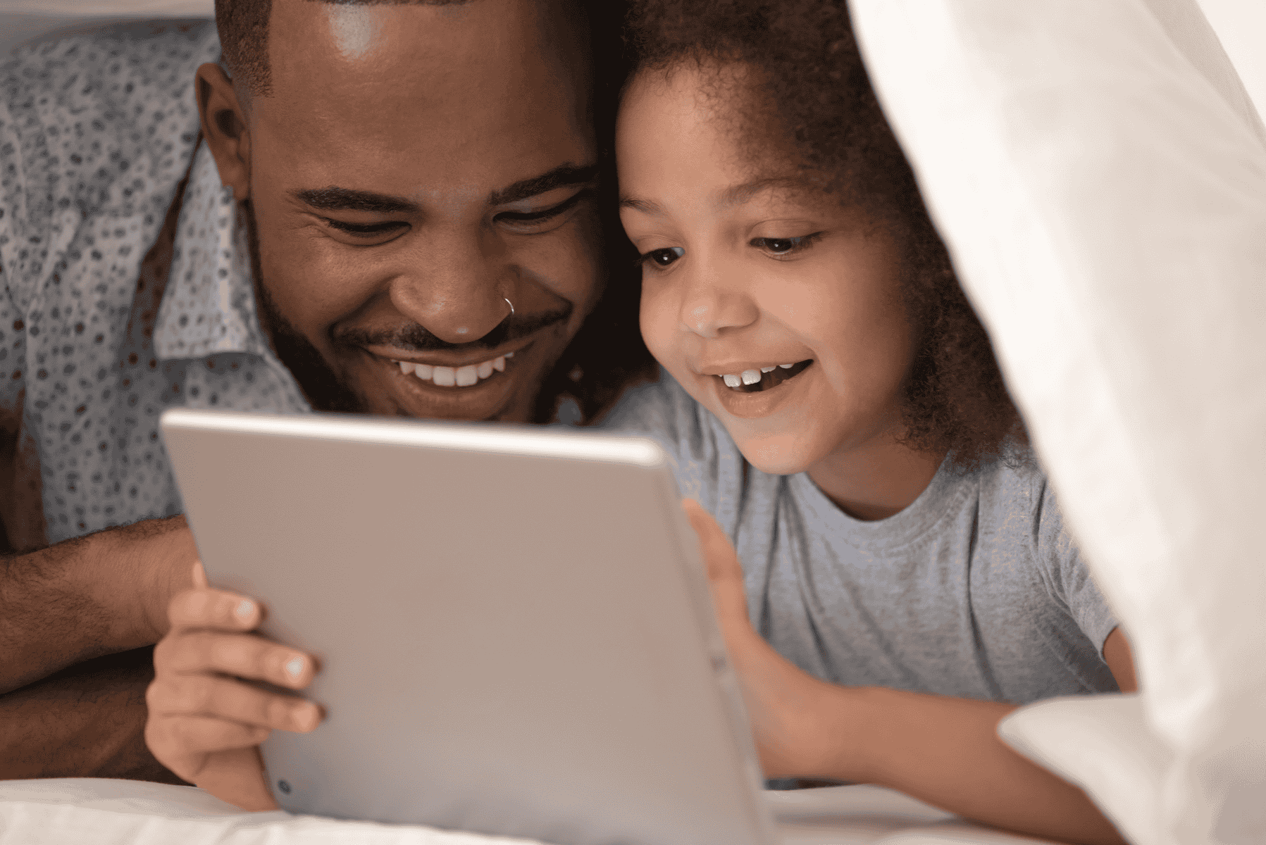 Father and daughter looking at a tablet in a play tent
