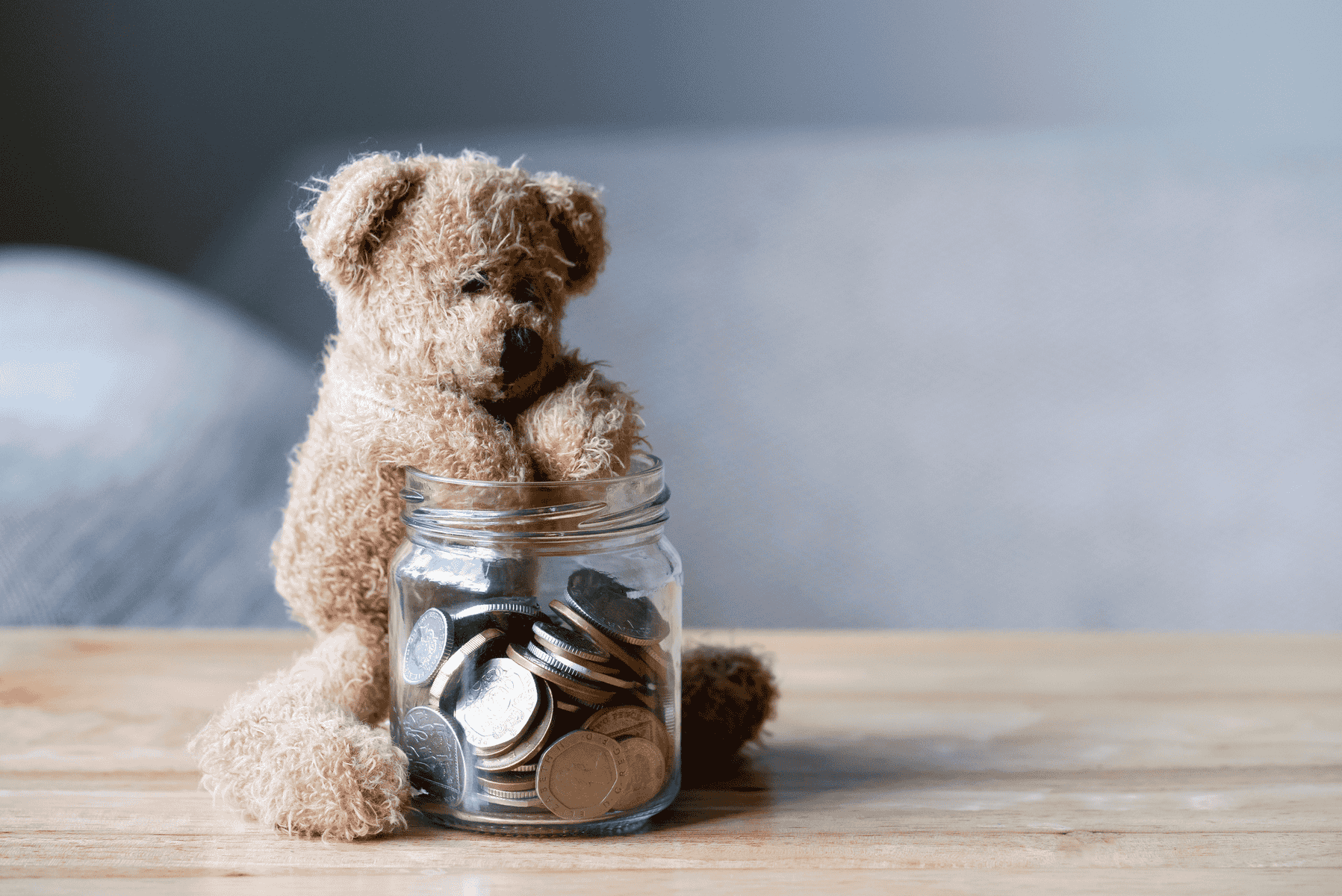 Teddy bear with its paws in a jar of money