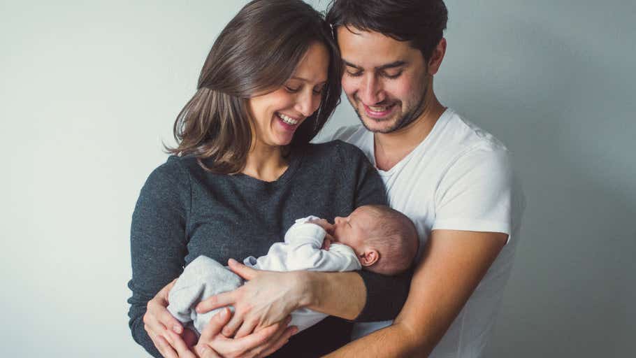 Portrait of young smiling family with newborn