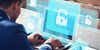 Young businessman working on his laptop in the office, select the icon security on the virtual display.